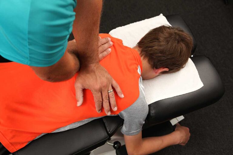 Person noticing tingling in a hand while seated at a desk beside a symptom journal.