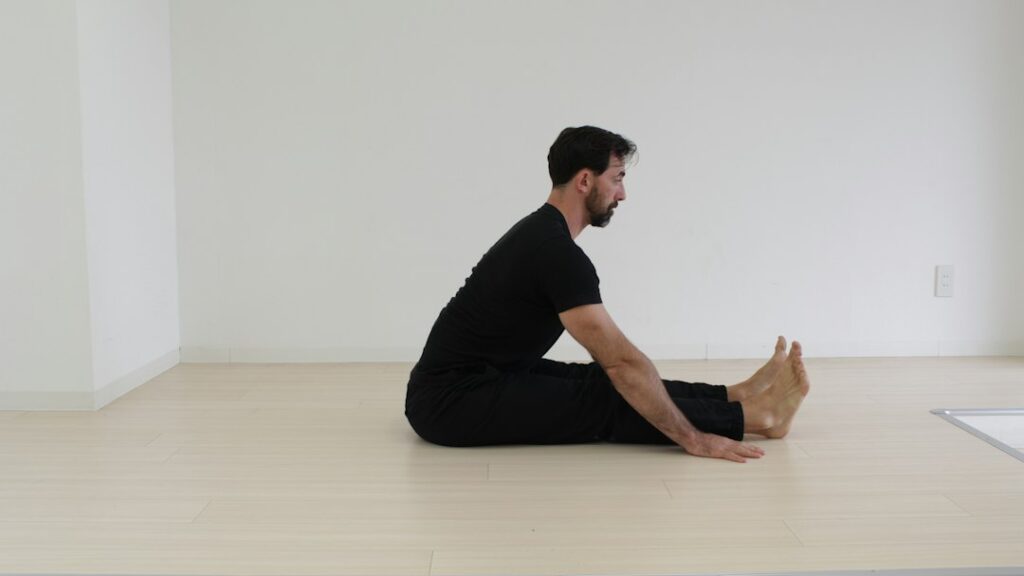 Person performing gentle mobility exercises beside a sturdy chair in a bright home setting.