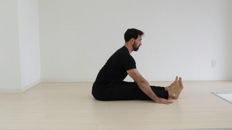 Person performing gentle mobility exercises beside a sturdy chair in a bright home setting.